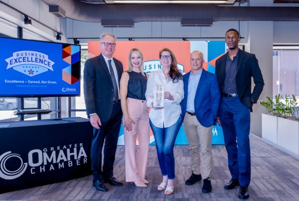 Omaha Chamber Business Excellence Award Winner Holland Basham Architects posed with plaque at ceremony