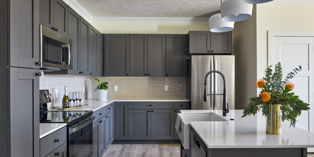 apartment kitchen with dark cabinets, wood flooring and quartz countertops