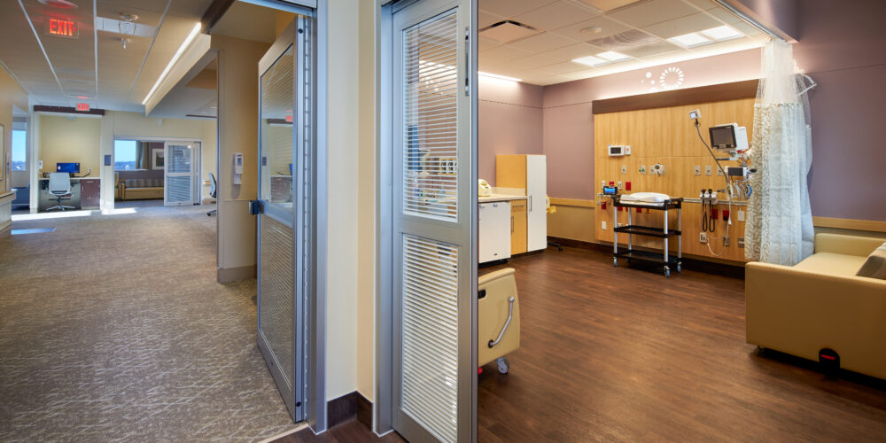 View from hallway of NICU unit patient room with colorful walls and warm, bright lighting.