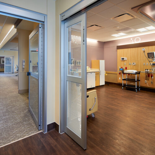 View from hallway of NICU unit patient room with colorful walls and warm, bright lighting.