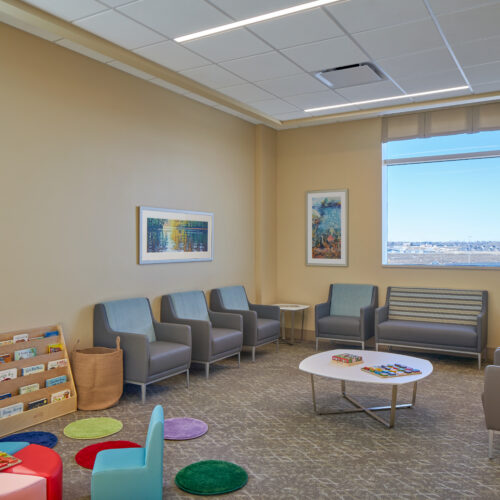 Waiting room with window overlooking the view and colorful furniture and books for kids.