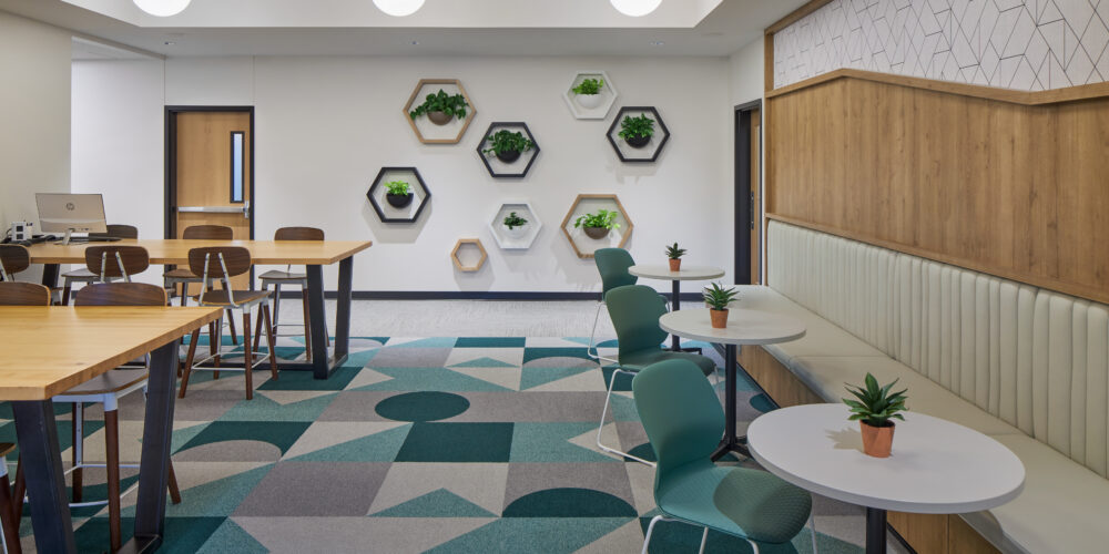 office coworking space with hightop tables and bench seating. natural tones with wood accents and bright geometric flooring